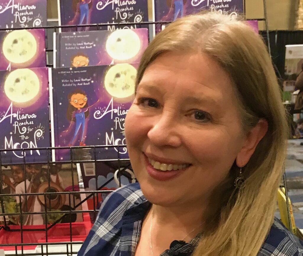 Image of children's book author Laura roettiger standing in front of a display of her books