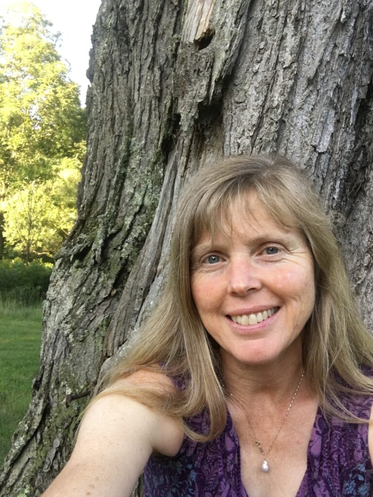 Image of children's book author Susanna Leornard Hill standing in front of a tree trunk.